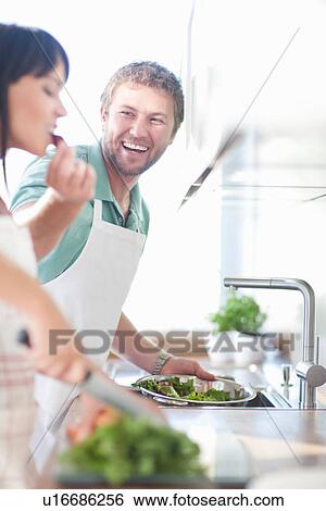 Couple preparing food, man feeding woman View Large Photo Image Stock Photograph - Couple preparing food, man feeding woman. Fotosearch