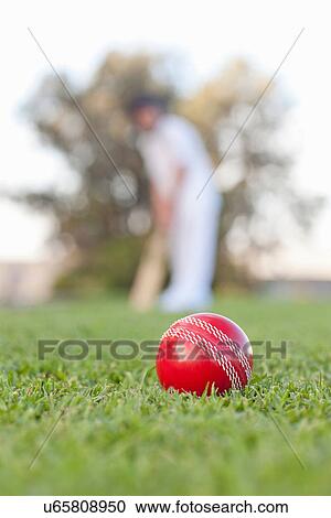 Stock Image - Cricket ball with man in background. Fotosearch