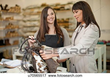 Customer and shop assistant looking at leather bag View Large Photo Image Stock Photo - Customer and shop assistant looking at leather bag. Fotosearch