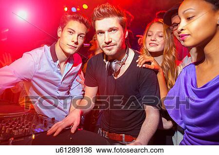 Stock Photograph - Disc Jockey surrounded by group of people. Fotosearch