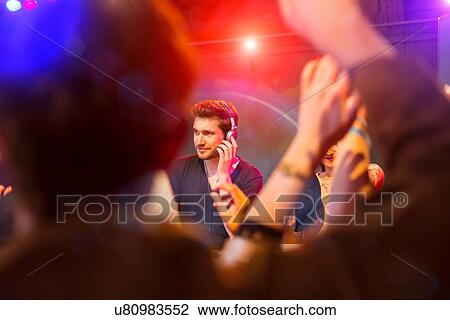 Stock Image - Disc jockey surrounded by people dancing. Fotosearch