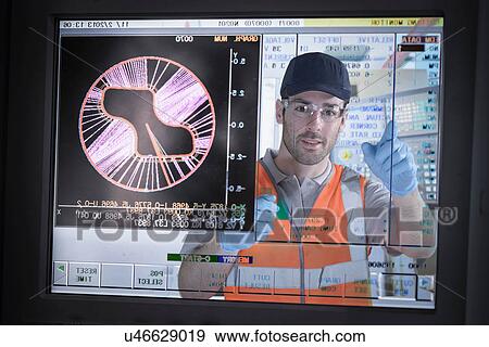 Stock Photo - Engineer operating cutting machine, view through screen. Fotosearch