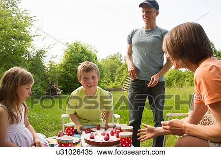 Stock Photography - Family outdoors having birthday picnic. Fotosearch