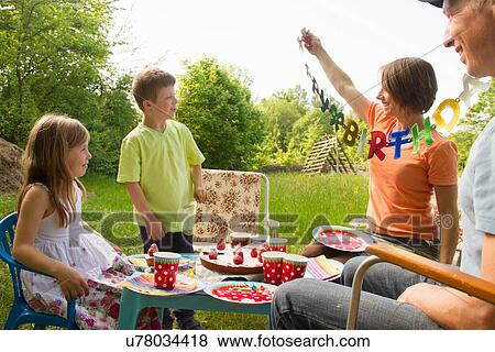 Stock Photo - Family with two children celebrating birthday outdoors. Fotosearch