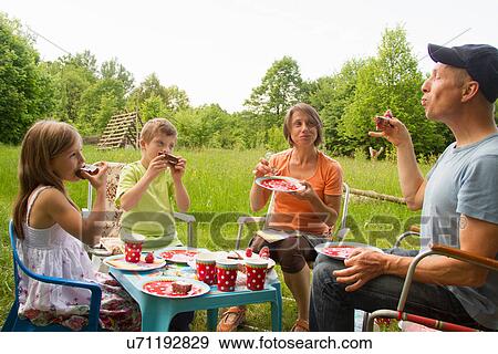 Stock Photo - Family with two children enjoying birthday cake picnic. Fotosearch