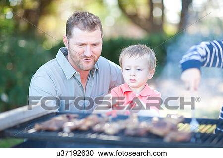 Stock Image - Father and sons barbecuing. Fotosearch