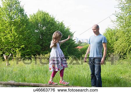 Father watches daughter balancing on tree trunk View Large Photo Image Stock Photograph - Father watches daughter balancing on tree trunk. Fotosearch