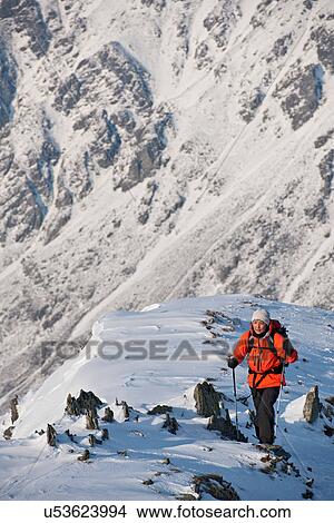 Picture - Female climber walking up snow covered ridge. Fotosearch