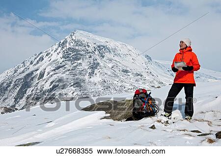 Stock Photography - Female climber with map on snow covered mountain, Carneddau, Snowdonia. Fotosearch
