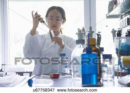 Stock Photo - Female scientist holding pipette and test tube. Fotosearch