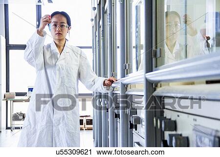 Female scientist holding up test tube View Large Photo Image Stock Image - Female scientist holding up test tube. Fotosearch