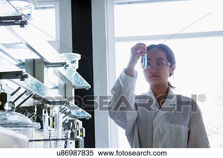 Stock Photography - Female scientist looking at test tube. Fotosearch