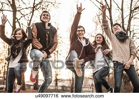 Stock Photograph - Five teenagers fooling around, jumping in park. Fotosearch