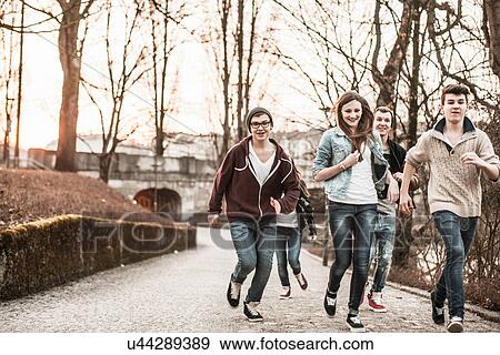 Stock Photo - Five teenagers running through park. Fotosearch