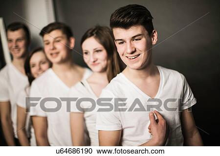 Stock Image - Five teenagers standing in row, all wearing white color top garments. Fotosearch