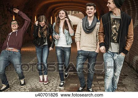 Stock Photograph - Five teenagers walking through tunnel laughing and joking. Fotosearch