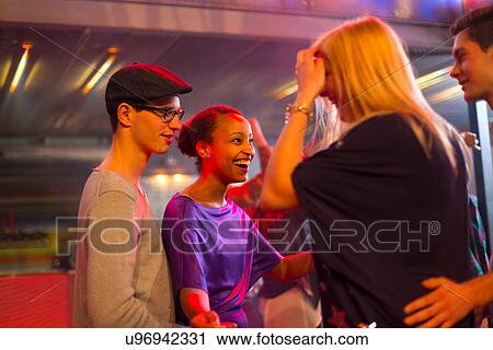 Stock Image - Four young adults laughing at party. Fotosearch