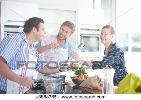 Stock Image - Friends cooking together in kitchen. Fotosearch