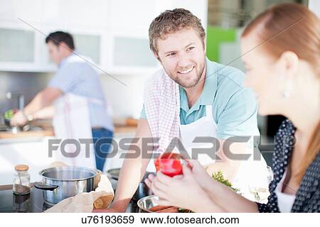 Friends cooking together in kitchen View Large Photo Image Stock Photo - Friends cooking together in kitchen. Fotosearch
