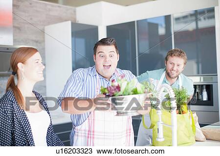 Stock Image - Friends preparing food together. Fotosearch