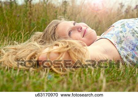 Stock Image - Girl lying down in a field. Fotosearch