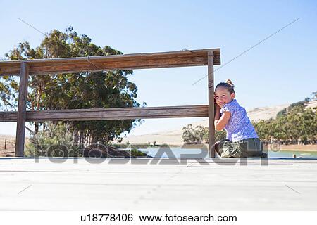Stock Photograph - Girl sitting on pier, looking over shoulder. Fotosearch