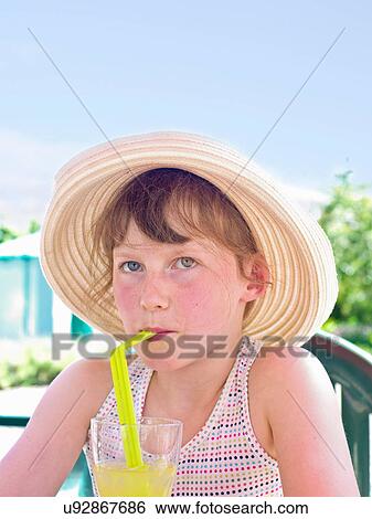 Stock Photograph - Girl wearing sunhat drinking soft drink. Fotosearch