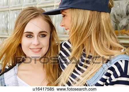 Stock Photography - Girlfriends laughing in front of glass wall. Fotosearch