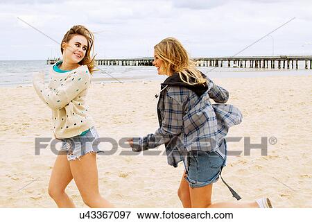 Stock Photo - Girlfriends playing chasing game on the beach. Fotosearch