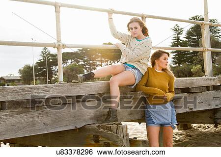 Girlfriends sitting on edge of pier View Large Photo Image Stock Photograph - Girlfriends sitting on edge of pier. Fotosearch