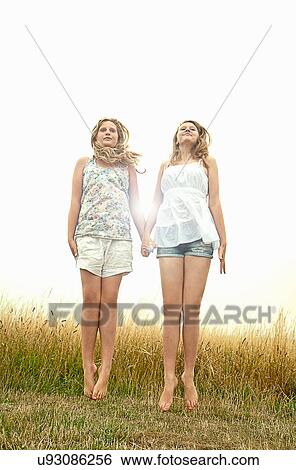 Girls in field, holding hands and jumping View Large Photo Image Stock Photograph - Girls in field, holding hands and jumping. Fotosearch