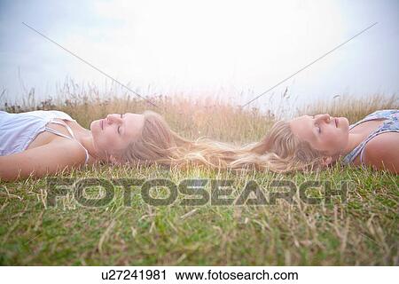 Girls lying in field, long hair entwined View Large Photo Image Stock Image - Girls lying in field, long hair entwined. Fotosearch