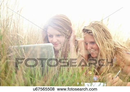Stock Photo - Girls using laptop in a field. Fotosearch