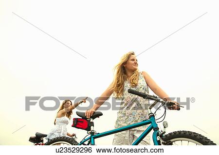 Girls with bikes, pointing View Large Photo Image Stock Photograph - Girls with bikes, pointing. Fotosearch