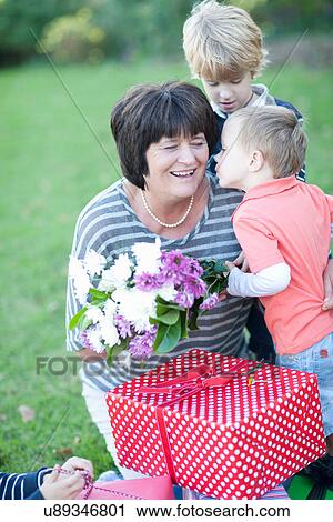 Stock Image - Grandmother with two grandsons and birthday gift. Fotosearch