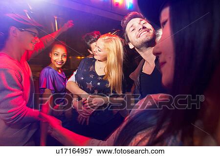 Stock Photo - Group of people at party, man kissing woman's neck. Fotosearch