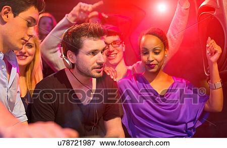 Stock Photo - Group of people dancing at party, man wearing headphones. Fotosearch