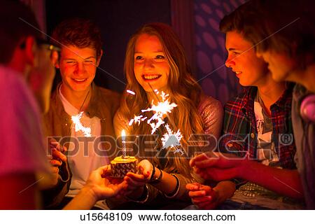 Stock Photo - Group of teenagers sitting around birthday cake with sparklers. Fotosearch