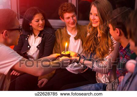 Stock Photography - Group of teenagers sitting around birthday cake. Fotosearch