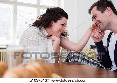 Stock Photo - Heterosexual couple holding hands at breakfast table. Fotosearch