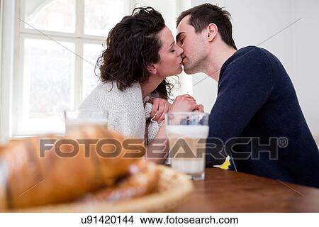 Heterosexual couple kissing at breakfast table View Large Photo Image Picture - Heterosexual couple kissing at breakfast table. Fotosearch