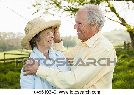 Stock Image - Husband adjusting wife's straw hat. Fotosearch