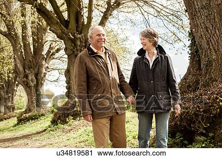 Husband and wife holding hands walking in park View Large Photo Image Stock Image - Husband and wife holding hands walking in park. Fotosearch