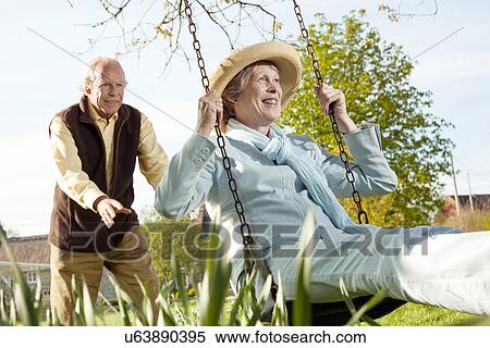 Husband pushing wife on swing View Large Photo Image Stock Photography - Husband pushing wife on swing. Fotosearch
