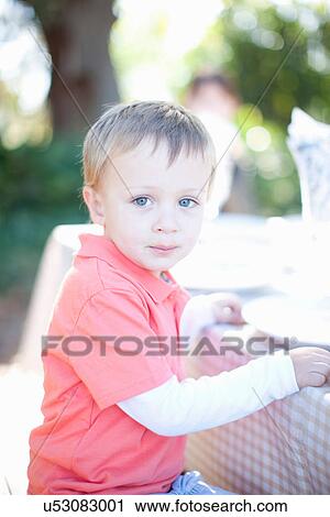 Stock Image - Little boy sitting at table outdoors. Fotosearch