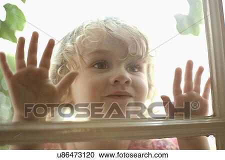 Stock Image - Little girl looking in through window. Fotosearch