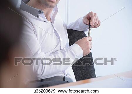Stock Photo - Man holding pen in business meeting, close up. Fotosearch