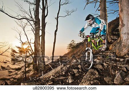 Stock Photography - Man mountain biking on rocks. Fotosearch