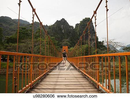 Man on bridge over river, Vang Vieng, Laos View Large Photo Image Stock Photograph - Man on bridge over river, Vang Vieng, Laos. Fotosearch
