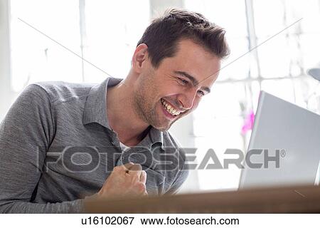 Stock Photo - Mature man looking at computer and smiling. Fotosearch